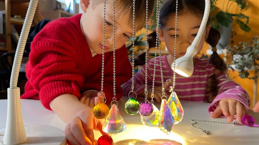 Child in a red sweater exploring light with crystals